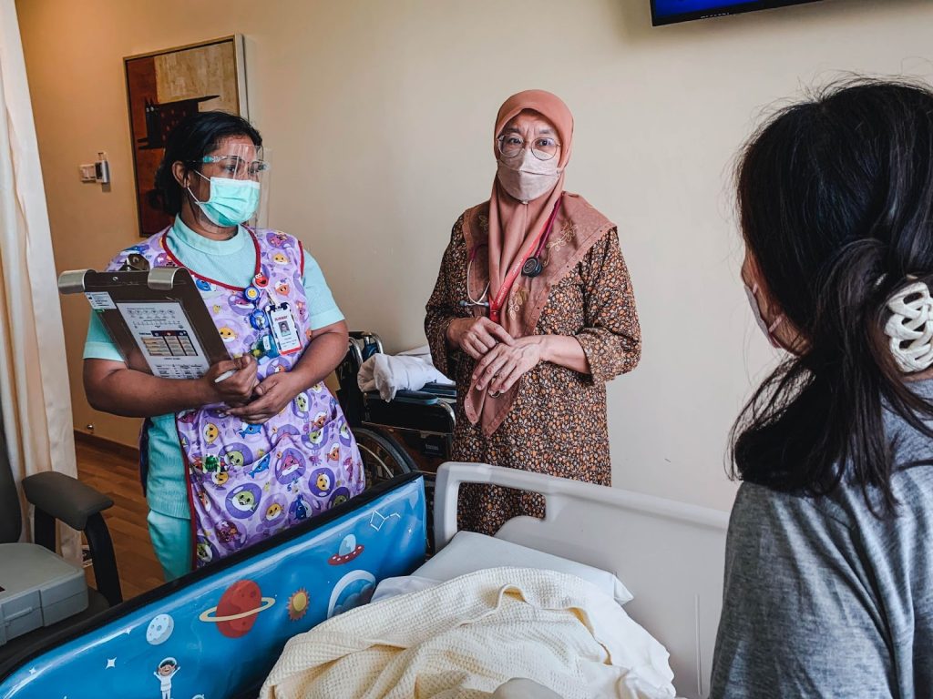 Oncologist Doctor Eni interacting with one of her patients with a nurse in the pediatric ward