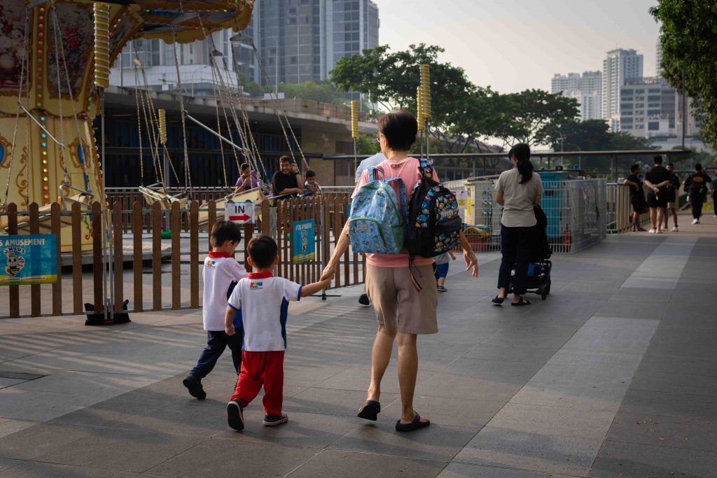 Image of a guardian walking with two children, seemingly of primary school age. 