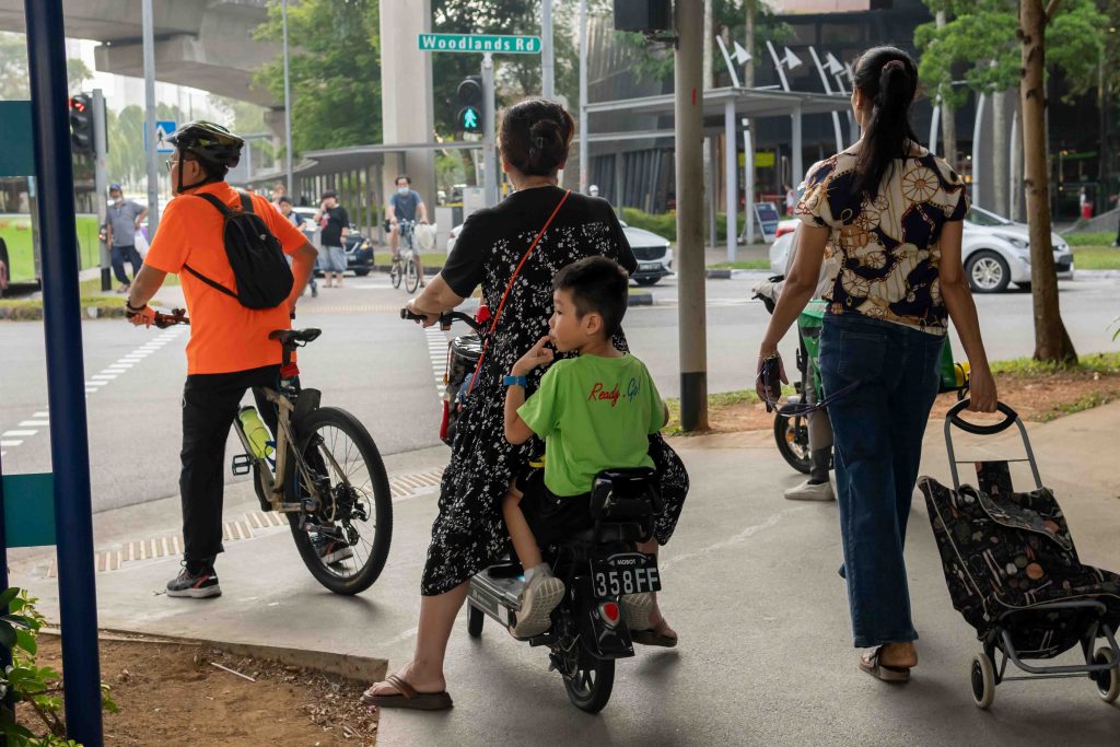 A primary school child sitting on the back of a electronic scooter. 